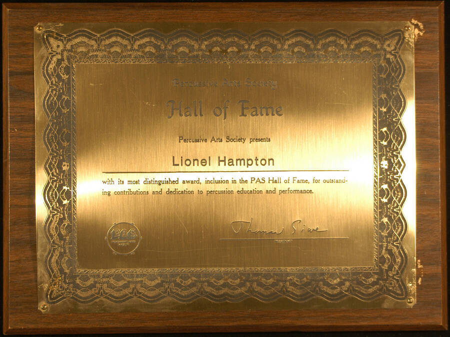 Plaque. 9"x12" Wood finish plaque with engraved certificate like plate Percussive Arts Society presents Lionel Hampton with his inclusion in the PAS Hall of Fame, for his outstanding contributions and dedication to percussion education and performance. Thomas Siwe, President. [1984-1986]