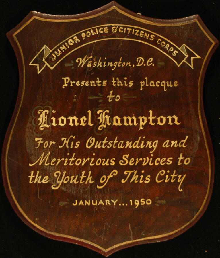 Plaque. 12"x10" Shield wood finish plaque with hand painted dedication To Lionel Hampton from the Junior Police and Citizens Corps of Washington, D.C. for his services to the Youth of this city. Washington, D.C., Jan. 1950