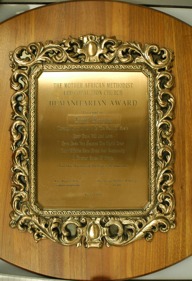 Plaque. 17"x13" Wood finish plaque with engraved plate inside casting To Lionel Hampton from the Mother African Methodist Episcopal Zion Church for furthering the cause of humanity. Mary C. Nehemiah, General Chairperson and George Weldom McMurray, Pastor. New York, NY, Mar. 27, 1983