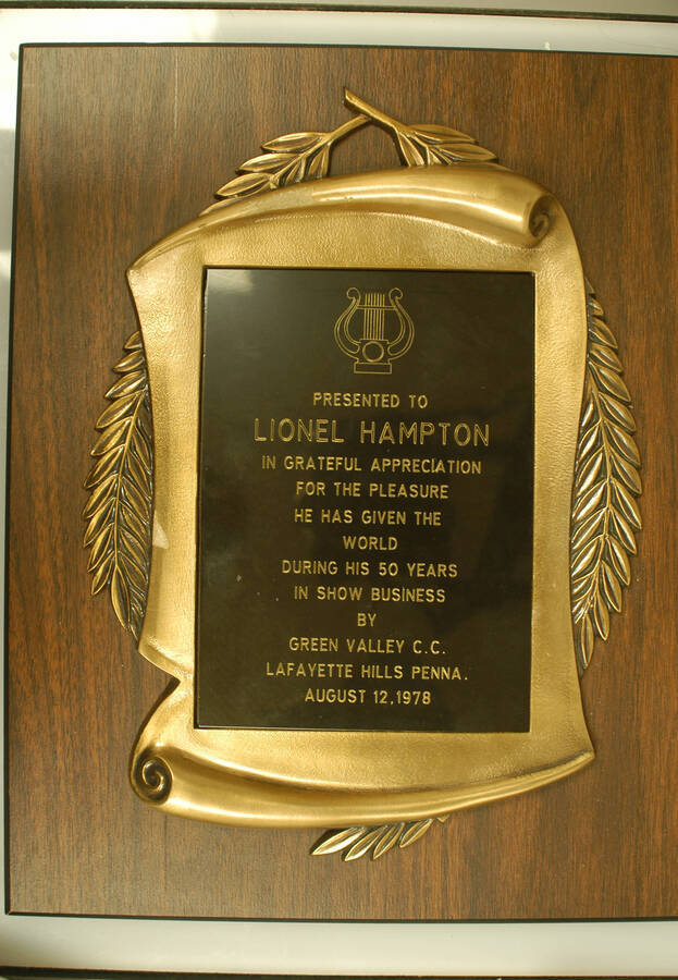 Plaque. 18"x12" Wood finish plaque with engraved plate inside scroll casting To Lionel Hampton from Green Valley C.C. Lafayette Hills Penna in grateful appreciation for the pleasure he has given the world during his 50 years in show business. [Pennsylvania] Aug. 12, 1978