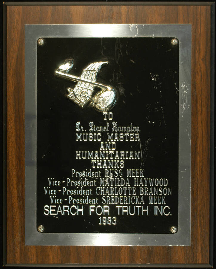 Plaque. 15"x12" Wood finish plaque with musical theme and engraved doubled plate To Lionel Hampton from Search for Truth. Russ Meek, President and others. 1983