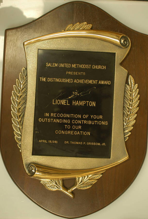 Plaque. 16"x11" Shield wood finish plaque with engraved plate inside scroll casting Distinguished Achievement Award presented to Lionel Hampton by Salem United Methodist Church in recognition of his outstanding contributions to the congregation. Thomas P. Grissom, Jr. Apr. 19, 1981