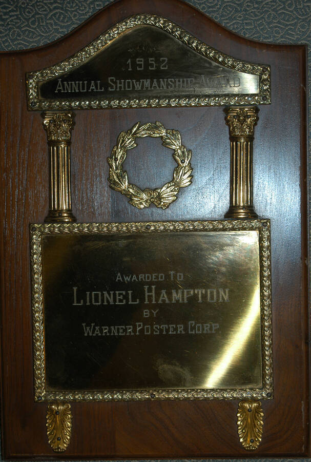 Plaque. 10"x15" Wood finish plaque with classical motifs  and two engraved plates Annual Showmanship Award presented to Lionel Hampton by Warner Poster Corp. 1952