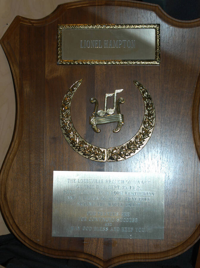 Plaque. 20"x16 1/2" Shield wood finish plaque with musical theme, laurel leaves in a crescent shape, and two engraved plates The Louisville branch of National Association for the Advancement of Colored People-NAACP pays tribute to a born Kentuckian and legion of music that folk around the world enjoy. Louisville, KY, Sep. 19, 1982