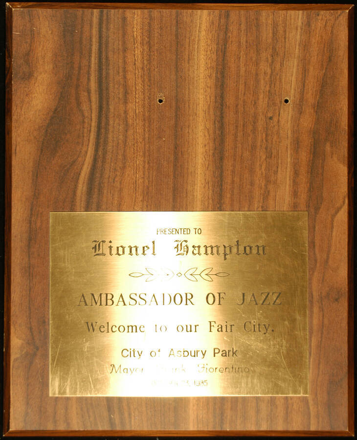 Plaque. 13"x10 1/2" Wood finish plaque with engraved plate To Lionel Hampton from the City of Asbury Park on occasion of his visit to the Fair City. Frank Fiorentino, Mayor. Asbury Park, NJ, Oct. 23, 1985