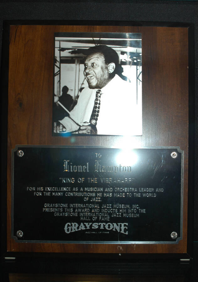 Plaque. 13"x10 1/2" Wood finish plaque with metal picture of Lionel Hampton and engraved double  plate Lionel Hampton is inducted into the Graystone International Jazz Museum Hall of Fame for his excellence as a musician and for the many contributions he has made to the world of jazz. [Detroit, MI]