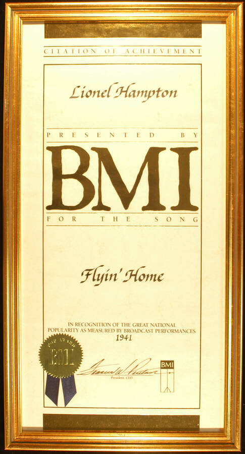 Framed Certificate. 20"x10" Certificate with gold foil seal and blue ribbon in an 21 1/4"x11 1/4" frame with glass Citation of Achievement presented to Lionel Hampton by BMI for the song Flyin' Home in recognition of the great national popularity as measured by broadcast performances. 1941