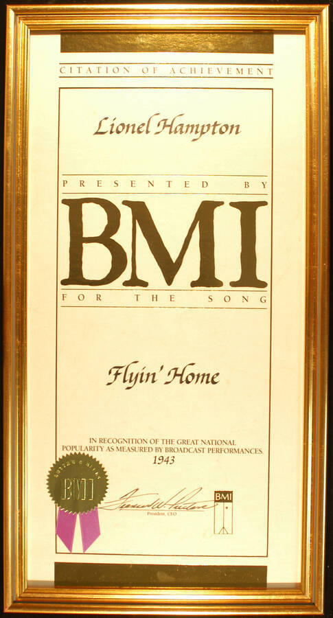 Framed Certificate. 20"x10" Certificate with gold foil seal and purple ribbon in an 21 1/4"x11 1/4" frame with glass Citation of Achievement presented to Lionel Hampton by BMI for the song Flyin' Home in recognition of the great national popularity as measured by broadcast performances. 1943
