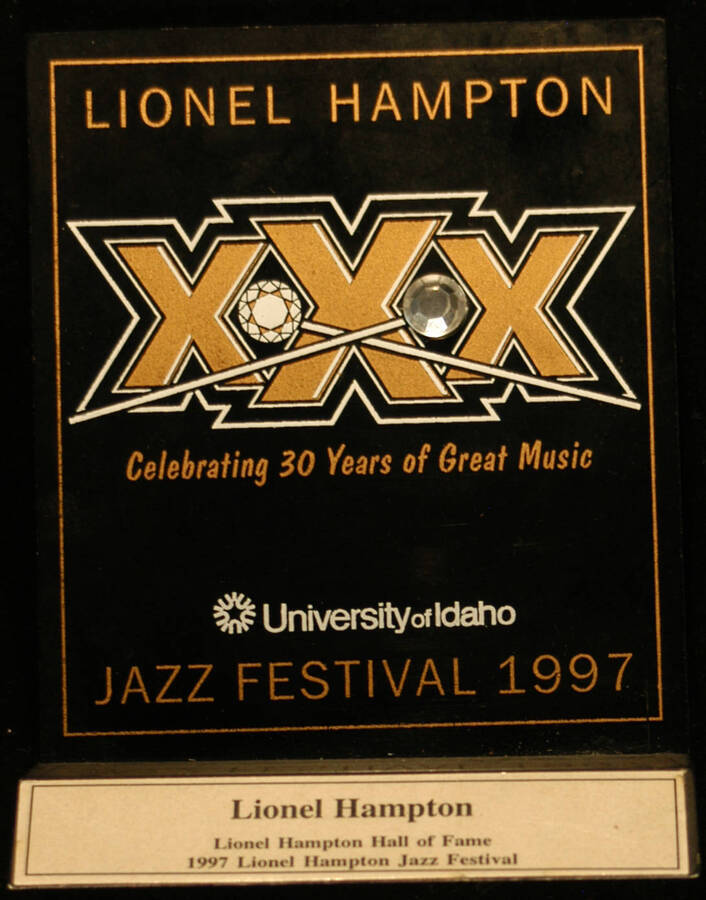 Plaque. 5 3/4"x4 3/4" Acrylic screen printed plaque on a 3"x5" wood base that reads "Lionel Hampton Hall of Fame" and bearing a 1"x3" gold plate from IAMAA University of Idaho Lionel Hampton Jazz Festival-1997 celebrating thirty years of great music. The plate is a 1998-Legacy Award to Lionel Hampton from the IAMAA/Harlem Arts Council and the Funds for Manhattan Arts. [Moscow, ID], 1997-1998