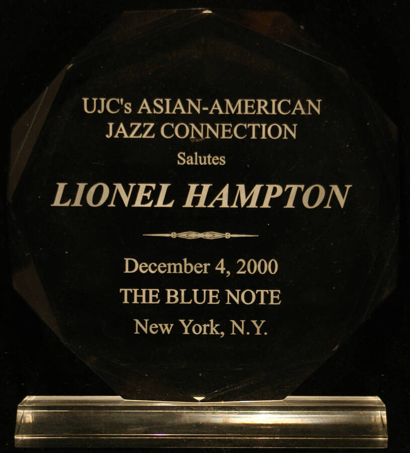 Plaque. 7"x7" Octagonal engraved clear acrylic plaque on 2"x6 1/2" clear acrylic base To Lionel Hampton from the [United Jewish Communities]-UJC's Asian-American Jazz Connection, at the Blue Note. New York, NY, Dec. 4, 2000