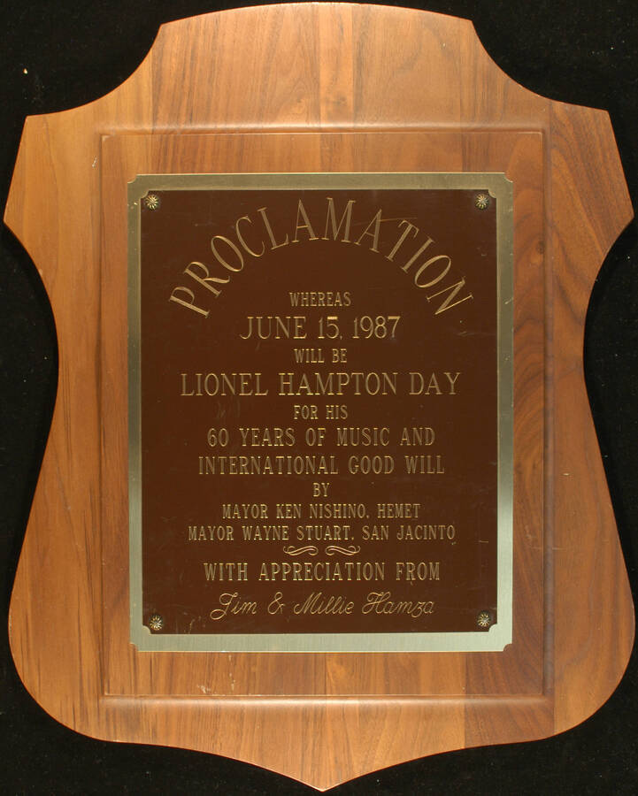 Plaque. 20"x16" Wood finish plaque with double engraved plate Cities of Hemet and San Jacinto proclaim June 15, 1987 as Lionel Hampton Day for his 60 years of music and international goodwill. Ken Nishino, Mayor of Hemet and Wayne Stuart, Mayor of San Jacinto. With appreciation from Jim and Millie Hamza. [Hemet, CA] Jun. 1987