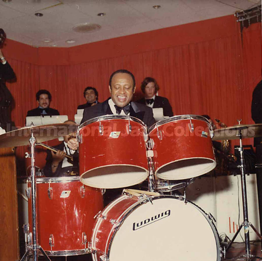 3 1/2 x 3 1/2 inch photograph. Lionel Hampton performing on drums with orchestra