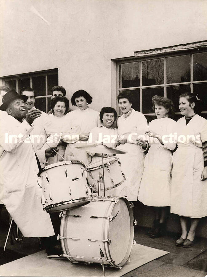 8 1/2 x 6 1/2 inch photograph. Lionel Hampton playing Trixon drums observed by unidentified women [in Germany]