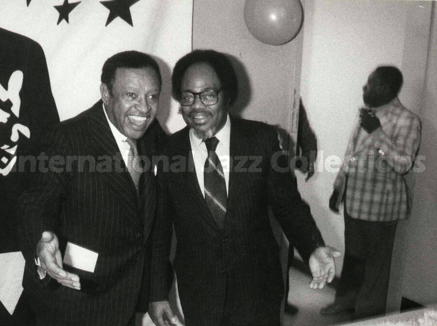 8 x 10 inch photograph. Lionel Hampton poses with Sir Roland Hanna on the occasion of his Birthday party. A plaque on the center of the birthday cake reads: Good Will Ambassador; Lionel Hampton Vibe President