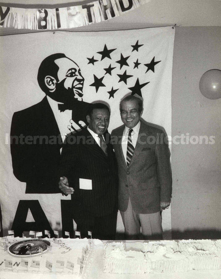 10 x 8 inch photograph. Lionel Hampton with unidentified man on the occasion of his Birthday party. A plaque on the center of the birthday cake reads: Good Will Ambassador; Lionel Hampton Vibe President