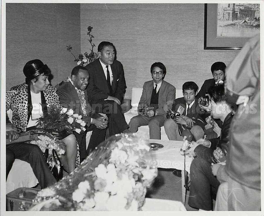 4 x 5 inch photograph. Gladys and Lionel Hampton with journalists [in Japan]