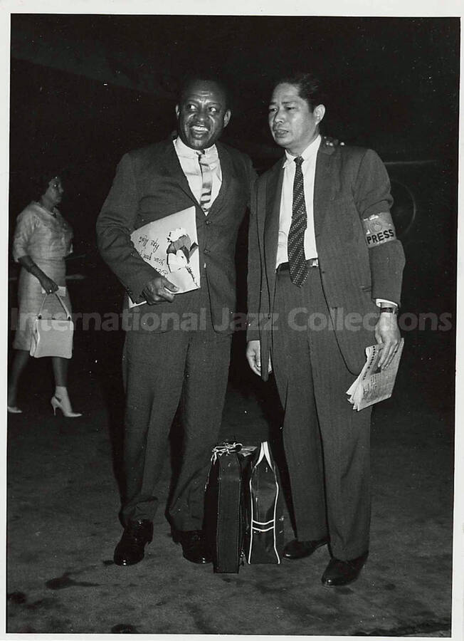 6 1/2 x 5 inch photograph. Lionel Hampton with a member of the press. Handwritten on the back of the photograph: Gene Feny[?], Tokyo