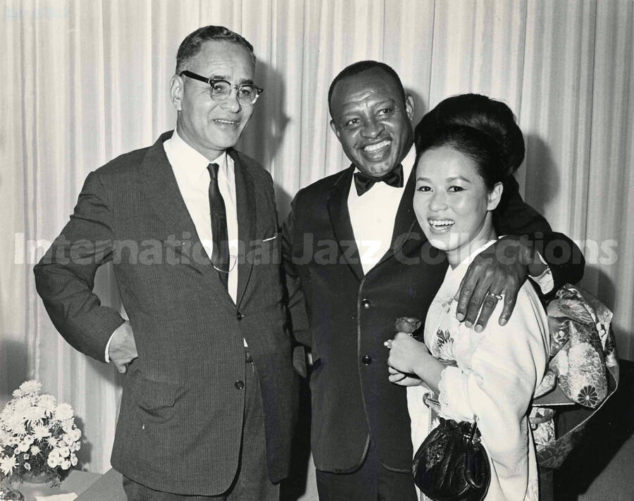 7 1/2 x 9 1/2 inch photograph. Lionel Hampton with unidentified man and a woman dressed in Japanese costume [Yukari Kuroda?]