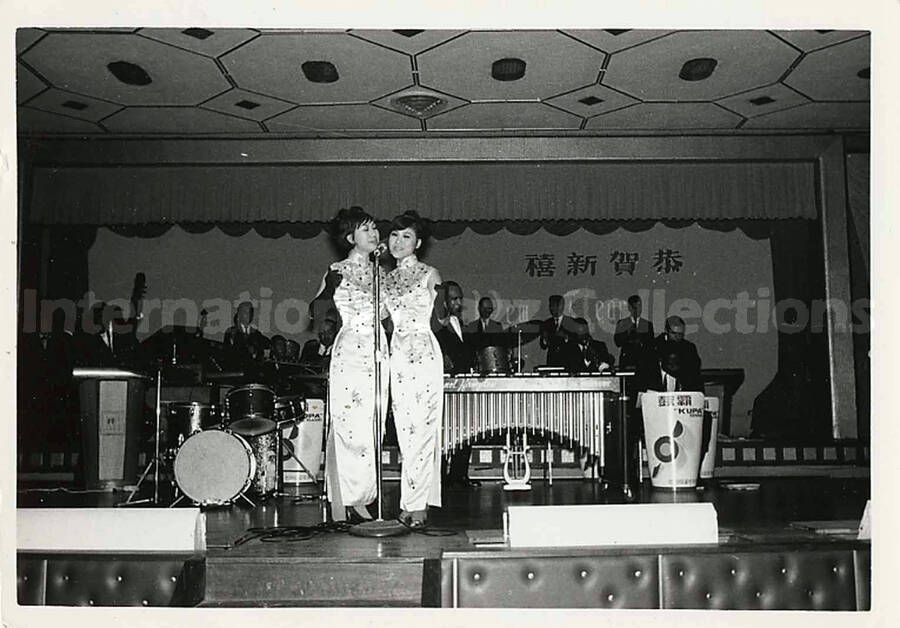 3 1/2 x 5  inch photograph. Lionel Hampton's band and two unidentified women dressed in Japanese costume, singing in Japan