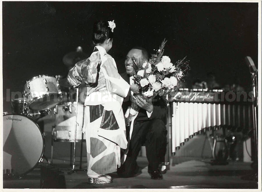 4 1/2 x 6 1/2 inch photograph. Lionel Hampton receives flowers from a girl dressed in Japanese costume