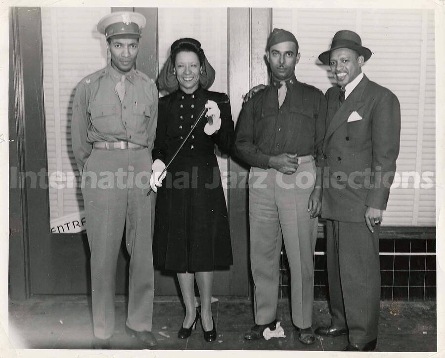 8 x 10 inch photograph. Lionel and Gladys Hampton posing with two unidentified military personnel