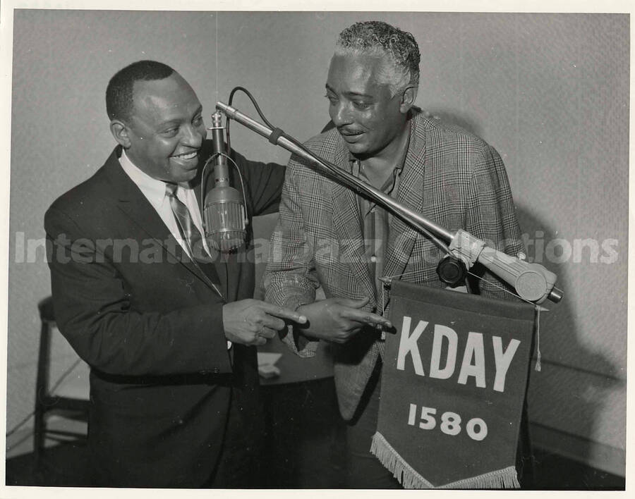 8 x 10 inch photograph. Lionel Hampton holding a banner of the radio station KDAY 1580 with unidentified man