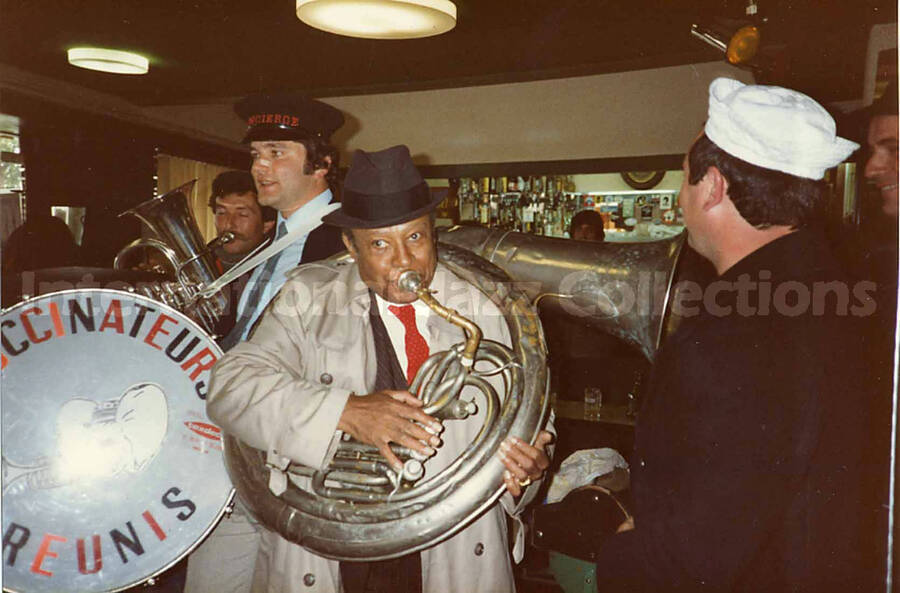 3 1/2 x 5 1/2 inch photograph. Lionel Hampton with the band Les Buccinateurs Reunis in a restaurant in [Bordeaux], France. This photograph is dedicated to Lionel, Bill, and Caprice, by Christian Dupin