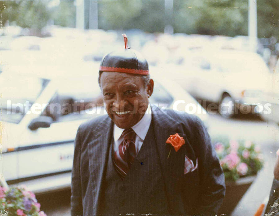 5 x 6 3/8 inch photograph. Lionel Hampton wearing a black and red hat with a white cross