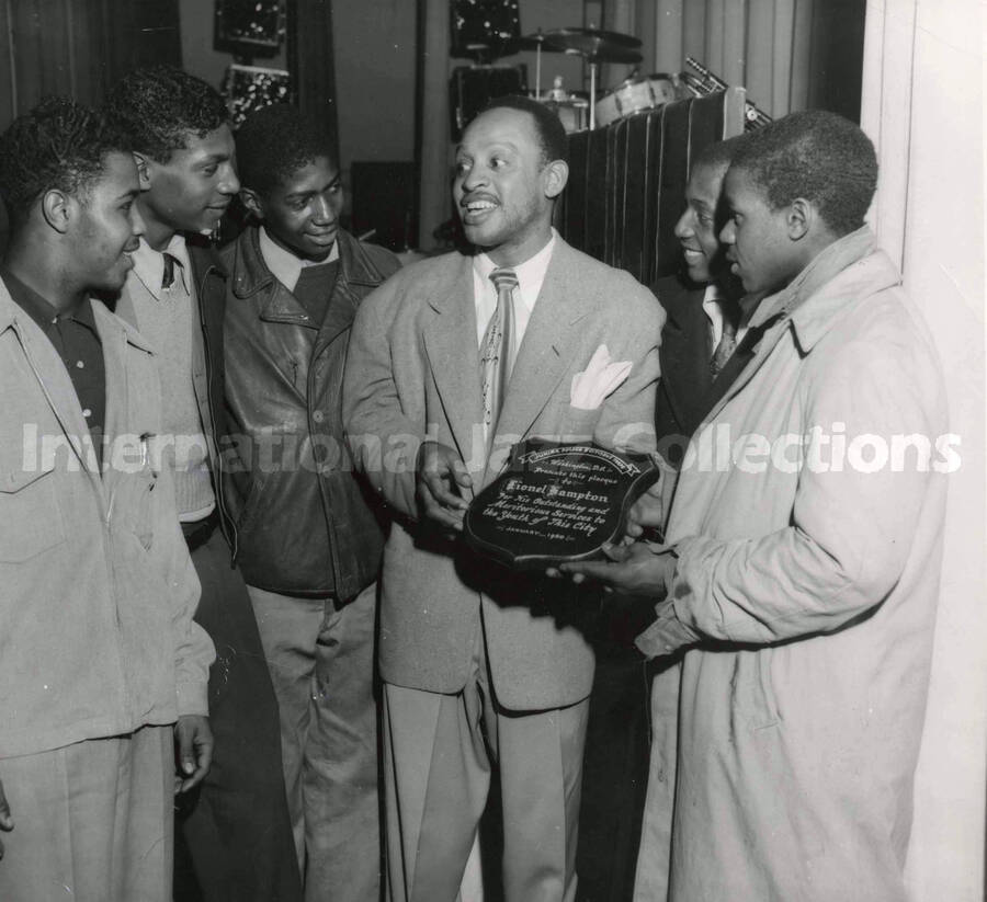 8 x 10 inch photograph. Lionel Hampton receives a plaque from the Junior Police and Citizens Corps of Washington, D.C. for his services to the youth of the city