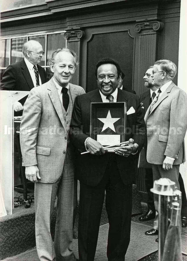 7 x 5 inch photograph. Lionel Hampton holding a plaque from the Hollywood Chamber of Commerce on the occasion of the placement of his star in the Walk of Fame. Los Angeles, CA