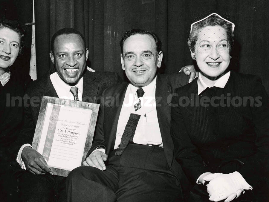 8 x 10 inch photograph. Lionel Hampton holding a plaque poses with members of the Los Angeles Chapter of Hadassah, on the occasion of his being awarded the certificate of the Hadassah Vocational Education Scholarship for his devotion to the State of Israel. Los Angeles, CA