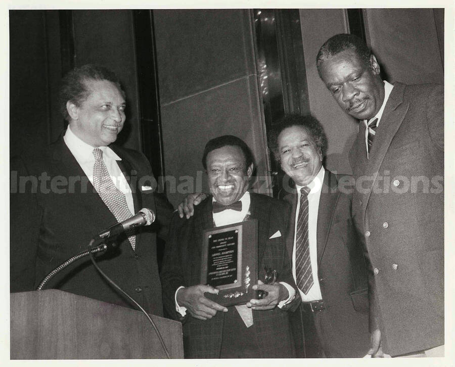 8 x 10 inch photograph. Lionel Hampton receiving the Henri M. Deas Award for Community Service, presented by the Opportunities Industrialization Center of New York. Milton A. Galamison is on Lionel Hampton's left side