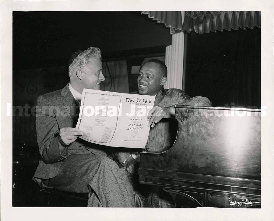 8 x 10 inch photograph. Lionel Hampton with unidentified man at the piano. They are holding a music sheet that reads: A Yiddishe Momme, by Jack Yellen and Lew Pollack