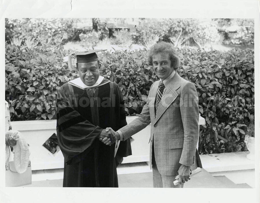 8 x 10 inch photograph. Lionel Hampton in graduation garb, poses with Bill Titone, [on the occasion of his receiving a honorary degree from Pepperdine University]