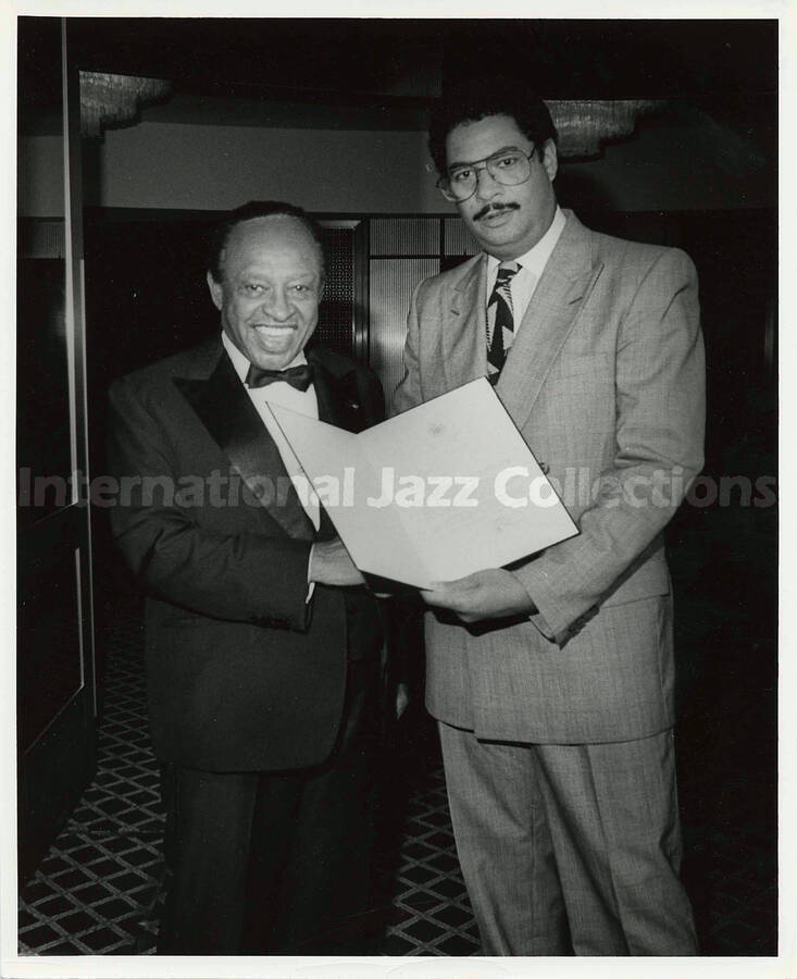 10 x 8 inch photograph. Lionel Hampton receives from an unidentified man, a letter by Edward I. Koch, Mayor of the City of New York, congratulating him for the Lifetime Achievement Award of B'nai B'rith