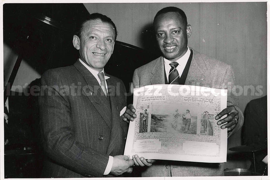 5 x 7 1/2 inch photograph. Lionel Hampton receiving the certificate from the Golden Book of the Jewish National Fund, upon the completition of a series of performances for the benefit of the Magen David Adom Fund in Israel