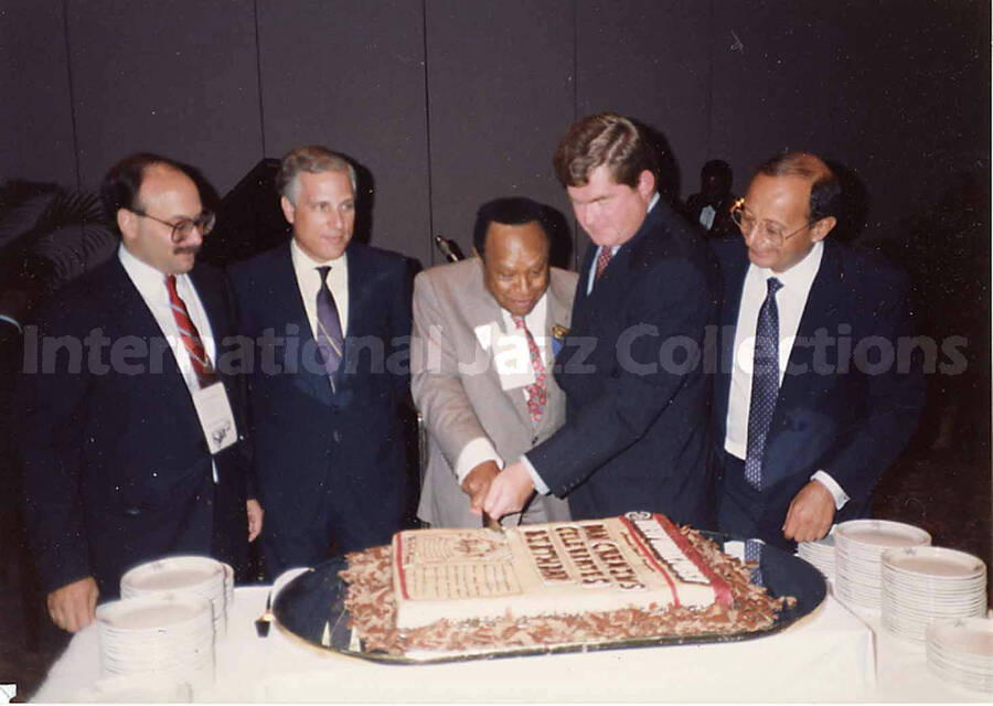 3 1/2 x 5 inch photograph. Lionel Hampton cutting a cake in the presence of four unidentified men, on the occasion of the Republican National Convention, in New Orleans, LA. The cake is modeled after a front page from the newspaper New York Post
