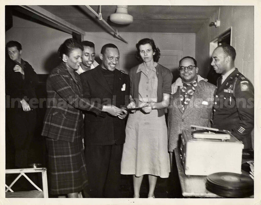8 x 10 inch photograph. Lionel Hampton with unidentified persons, including a military man. On the man's shoulder is the AA patch of the 82nd Airborne division