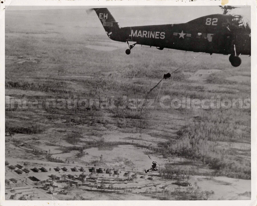 8 x 10 inch photograph. A United States Marine helicopter delivering a parachutist. Inscribed on the helicopter: EH 82 Marines