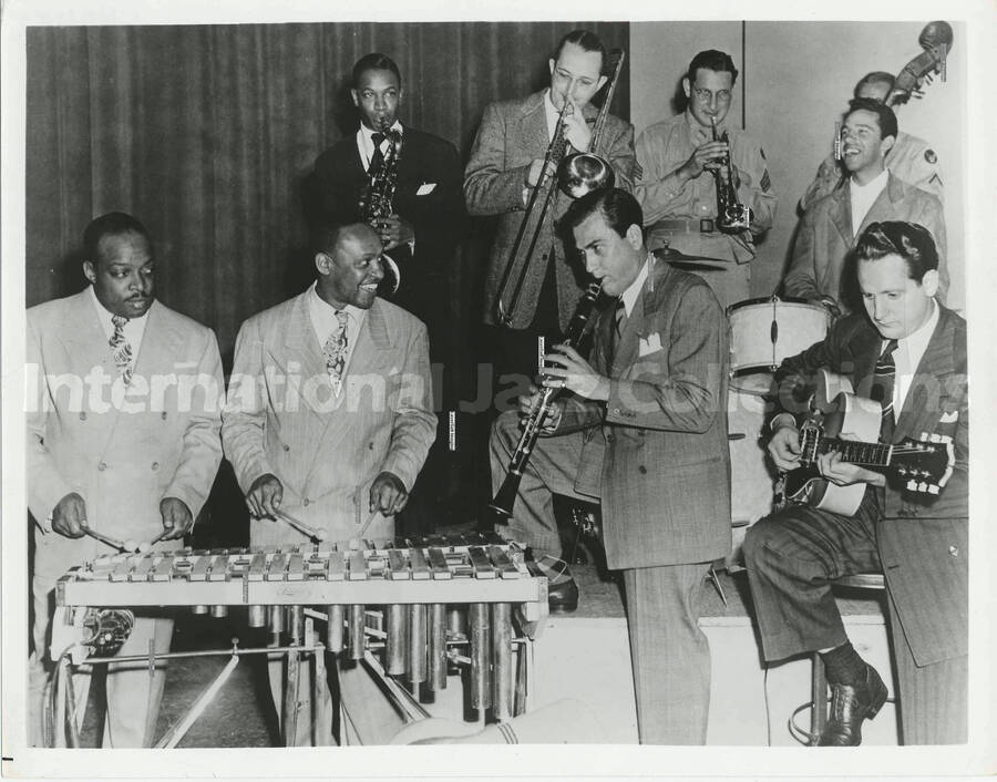 8 x 10 inch photograph. Highlights of 1944 Command Performance program on the Armed Forces Radio Service, ensemble performing: Honeysuckle Rose. Produced in Hollywood.  L to r.: Count Basie (vb), Lionel Hampton (vb), Artie Shaw (cl), Les Paul (gtr), llinois Jacquet (tnr sax), Tommy Dorsey (tbn), Ziggy Elman (tpt), Buddy Rich (dms), and Ed McKinney, obscured by Rich (bs)
