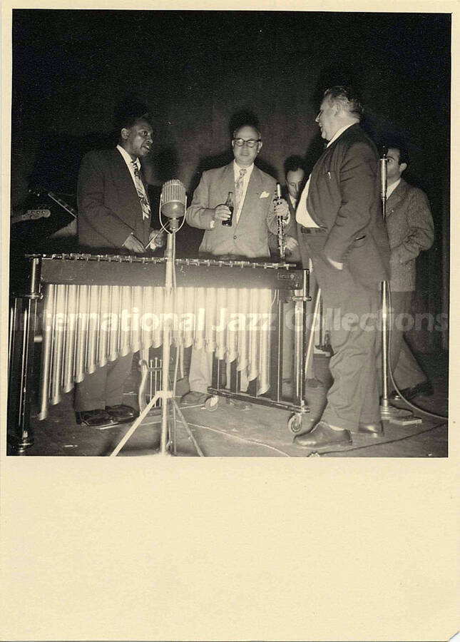 7 x 5 inch photograph. Lionel Hampton with four unidentified men standing around the vibraphone, probably in an interval of a recording session in Paris. This photograph is dedicated to Lionel Hampton from [Claude? or Claudio?]