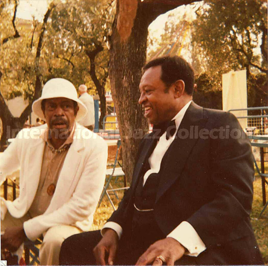 3 1/2 x 3 1/2 inch photograph. Al Grey and Lionel Hampton sitting on a bench in a park