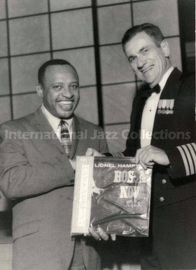 7 1/2 x 5 1/2 inch photograph. Lionel Hampton with unidentified man. They are holding the LP Lionel Hampton Bossa Nova Jazz. This photograph is stamped on the back with [Japanese characters?]