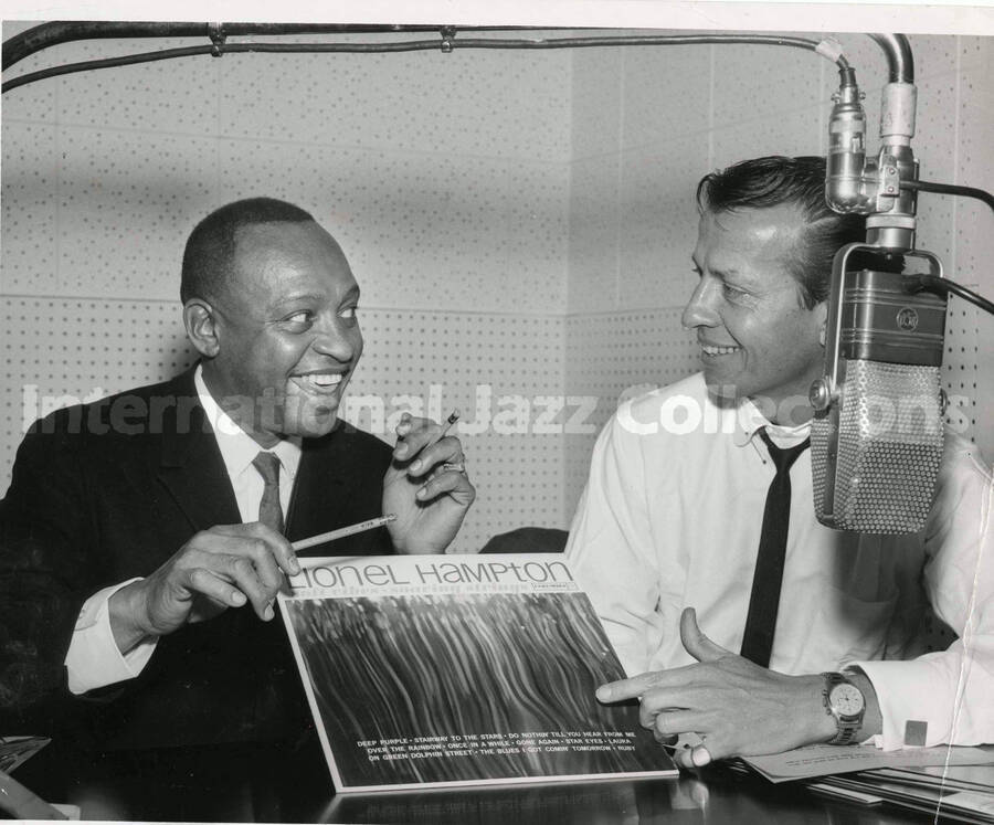 8 x 10 inch photograph. Lionel Hampton with unidentified man in a RCA studio. They are holding a copy of the record Lionel Hampton: soft vibraphone, soaring strings (Columbia)
