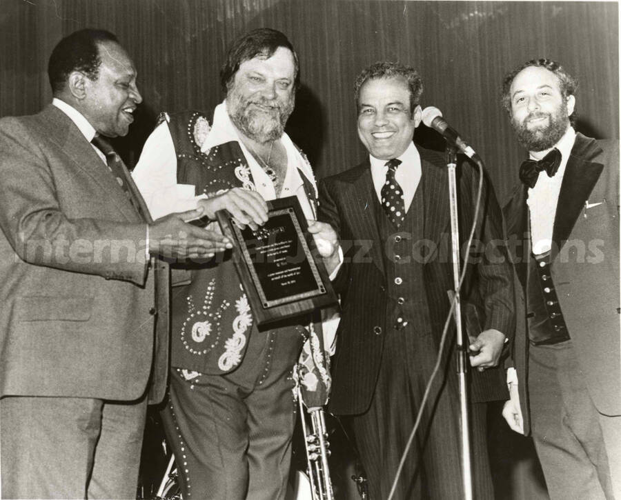 8 x 10 inch photograph. Lionel Hampton with [Al Hirt?] holding a plaque and two unidentified men