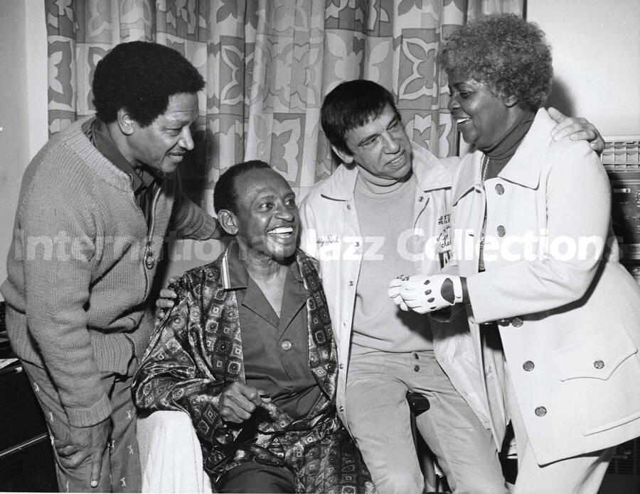 8 x 10 inch photograph. Illinois Jacquet, Buddy Rich, and Lucille Armstrong visits Lionel Hampton at a hospital