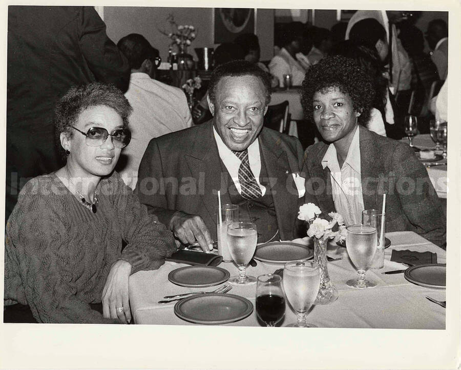 8 x 10 inch photograph. Lionel Hampton with two unidentified women in a restaurant