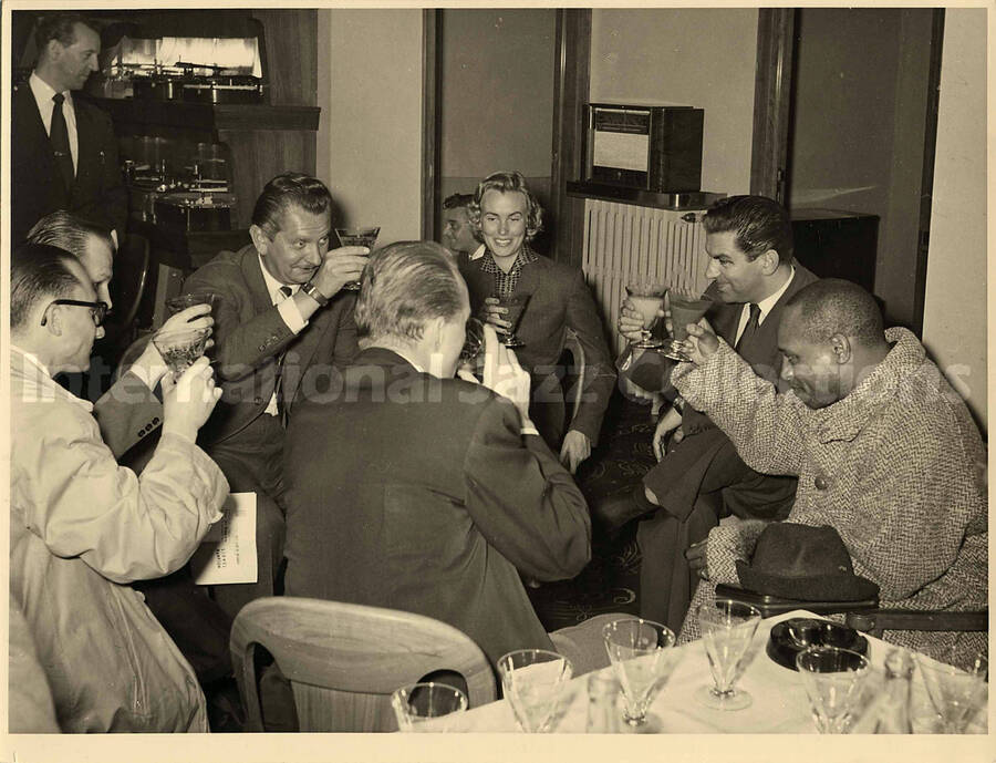8 x 10 inch photograph. Lionel Hampton, Bill Titone, and unidentified persons in a restaurant. Stamped on the back: With compliments of Gerard D. Pochonet