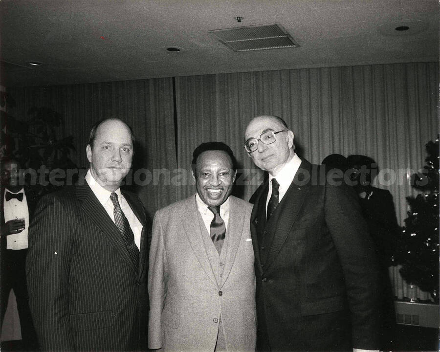 8 x 10 inch photograph. Lionel Hampton with two unidentified men, on the occasion of his receiving a plaque from the United States Mission that appointed him as Ambassador of Music to the United Nations. Handwritten on the back of the photograph: Arthur Milton
