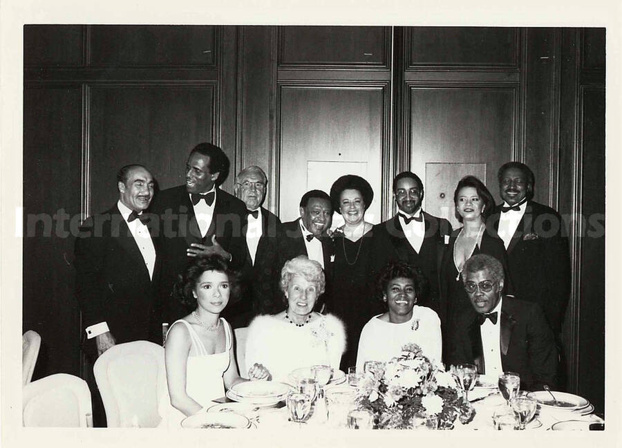 5 x 7 inch photograph. Lionel Hampton at a dinner table with unidentified persons, in a ceremony at the Garden City Hotel